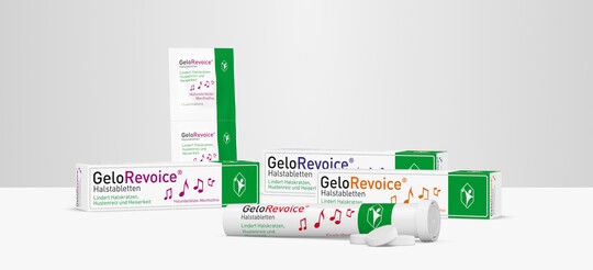 Verschiedene Verpackungen und eine geöffnete Tube von GeloRevoice® Halstabletten in verschiedenen Sorten, darunter Holunderblüte-Menthol und Kirsch-Menthol. Die Produkte stehen auf einer weißen Fläche vor einem grauen Hintergrund. GeloRevoice® lindert Halskratzen, Hustenreiz und Heiserkeit und unterstützt die Regeneration der Mund- und Rachenschleimhaut.