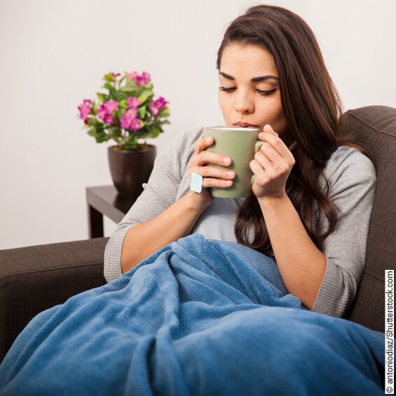 Frau krank mit Tasse auf dem Sofa