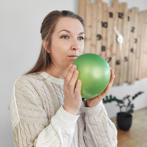 Frau summt gegen einen Luftballon als Stimmübung