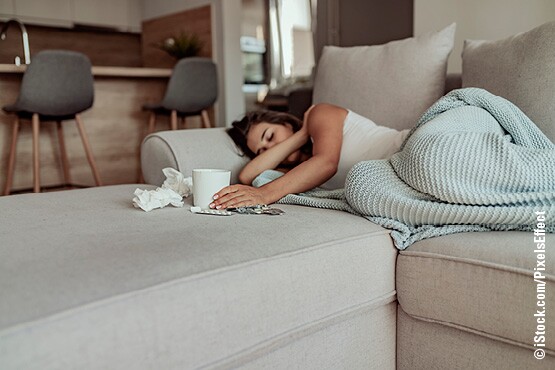 Frau mit Grippe liegt auf dem Sofa und leidet an Heiserkeit