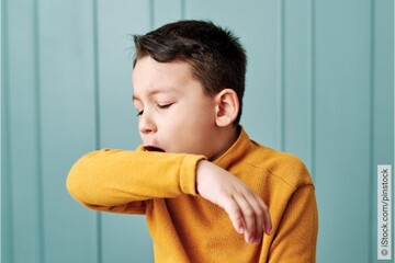 Junge mit Kehlkopfentzündung hustet in Armbeuge.